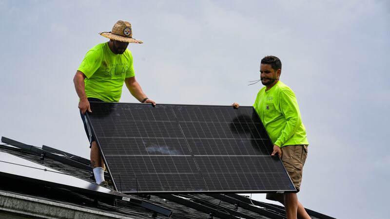 FILE - Even Berrios, left, and Nicholas Hartnett, owner of Pure Power Solar, install a solar...