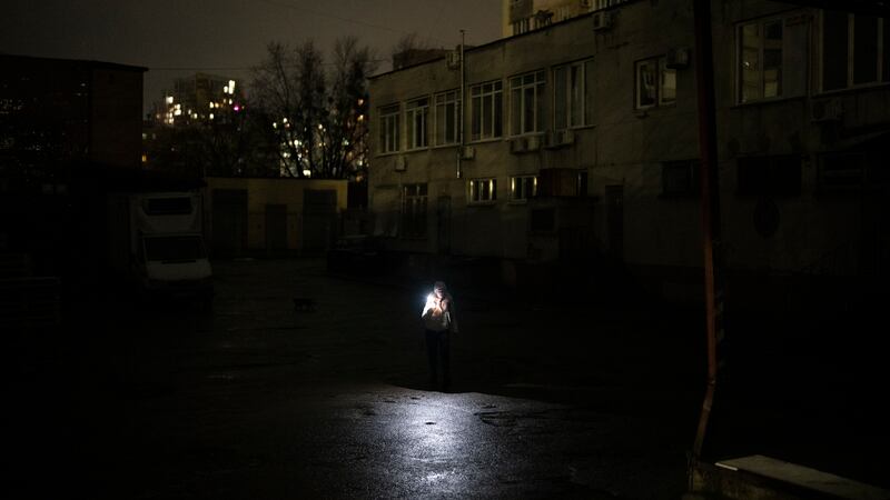 A woman uses her phone to light her way in Kyiv, Ukraine, Tuesday, Jan. 31, 2023.